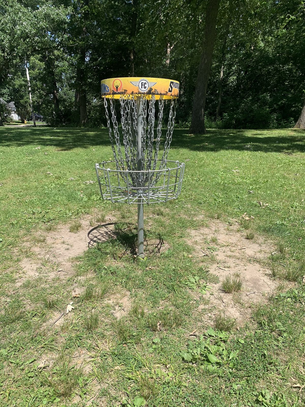 Yellow-banded disc golf basket on a park lawn in Loves Park, Illinois